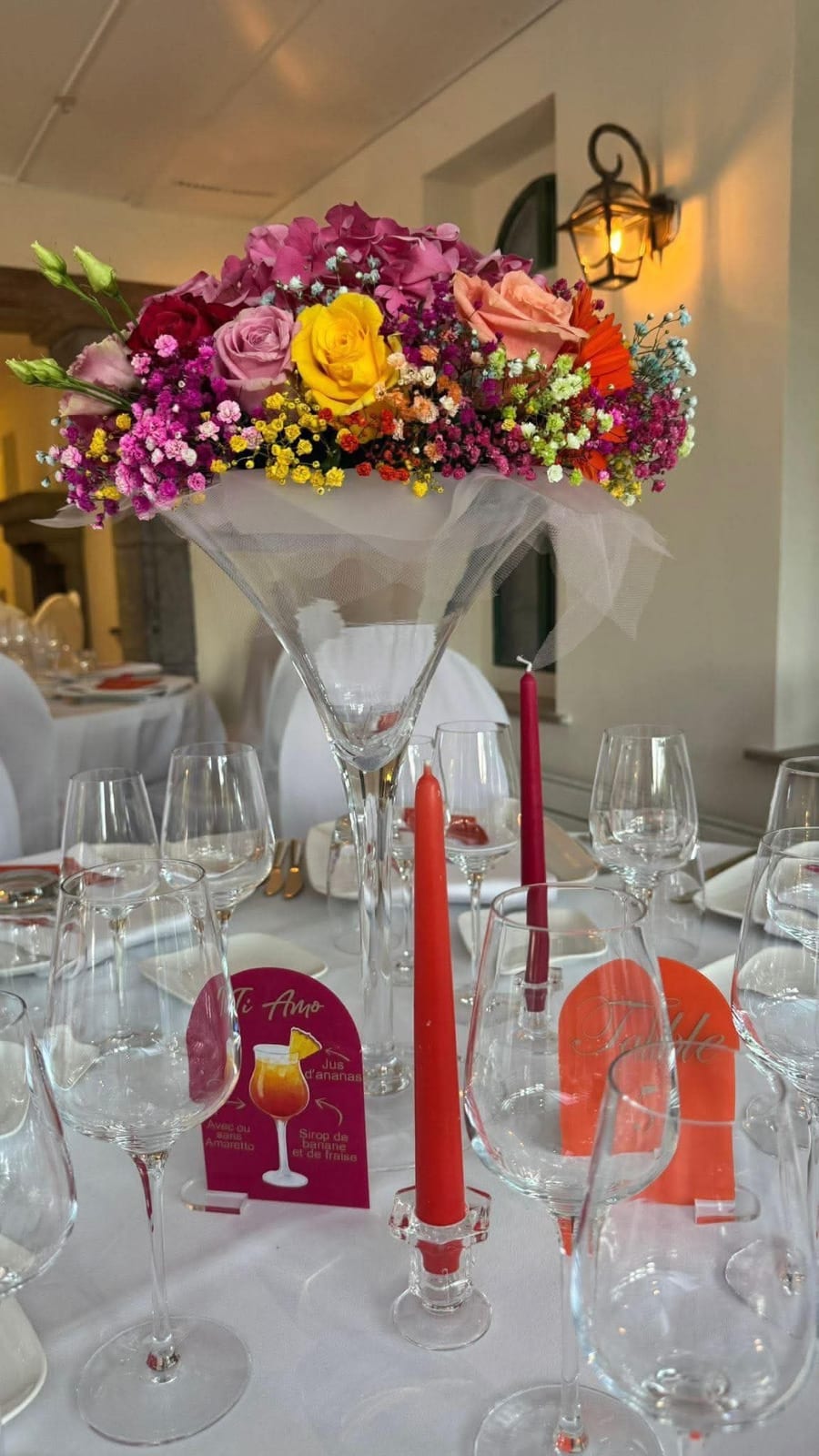 Vase martini garni de fleurs colorées sur table dressée